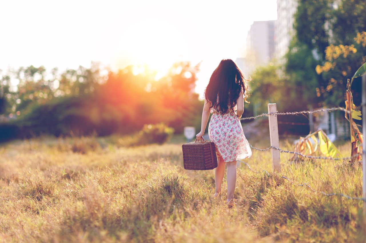 femme avec valise dans un champ
